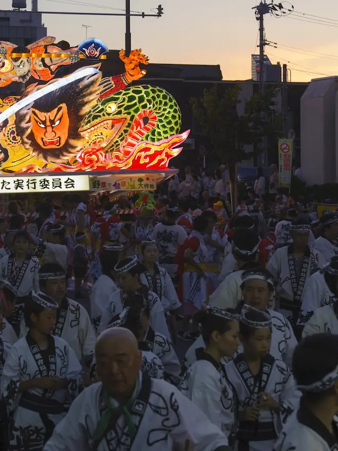 夕暮れの通りを埋める囃子方と跳人の列